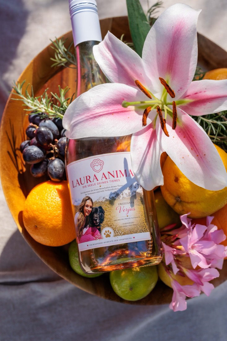Frizzante-Flasche in einer Obstschale mit Lilie