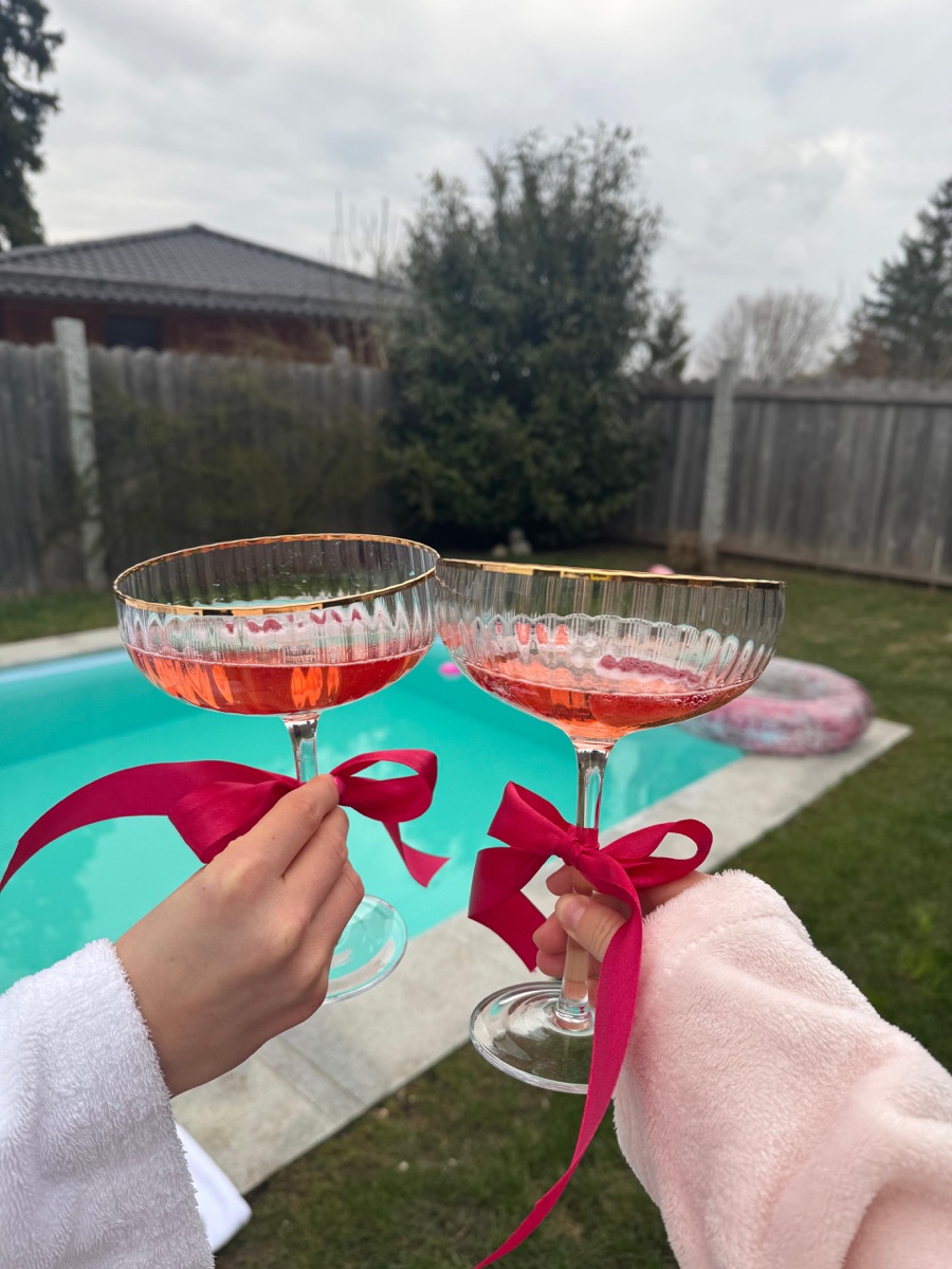 Zwei Coupe-Gläser Frizzante mit pinker Schleife am Pool